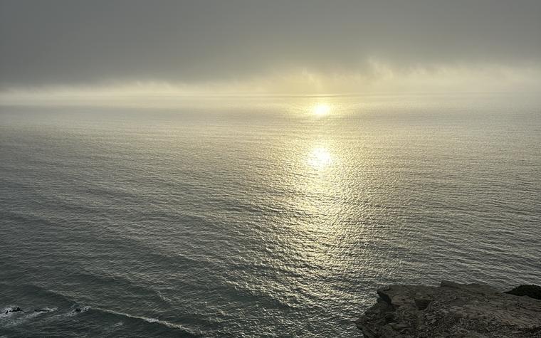 Light breaking through sea mist over open water