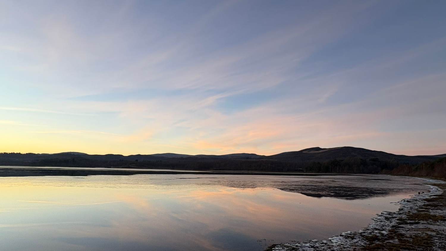 A loch at dusk, still water reflecting the sky